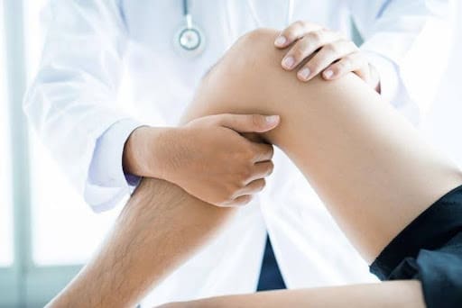 A doctor is holding the knee of a patient.