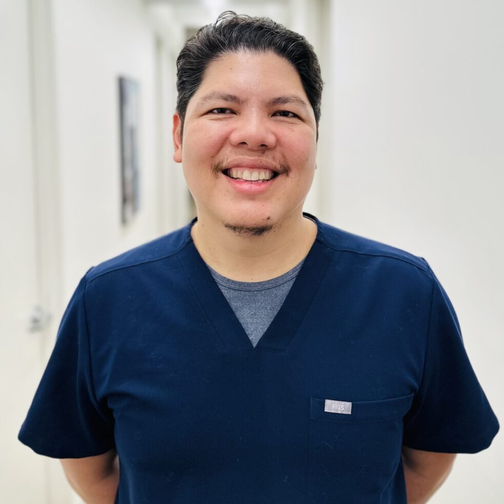 Smiling person in blue medical scrubs.