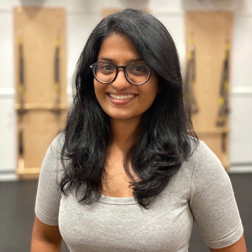 A woman with glasses standing in front of wooden walls.