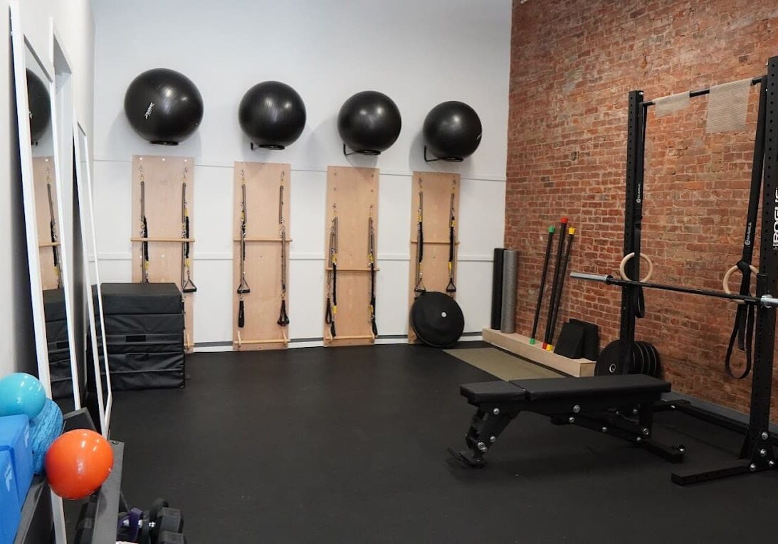 A gym with many equipment and a brick wall.