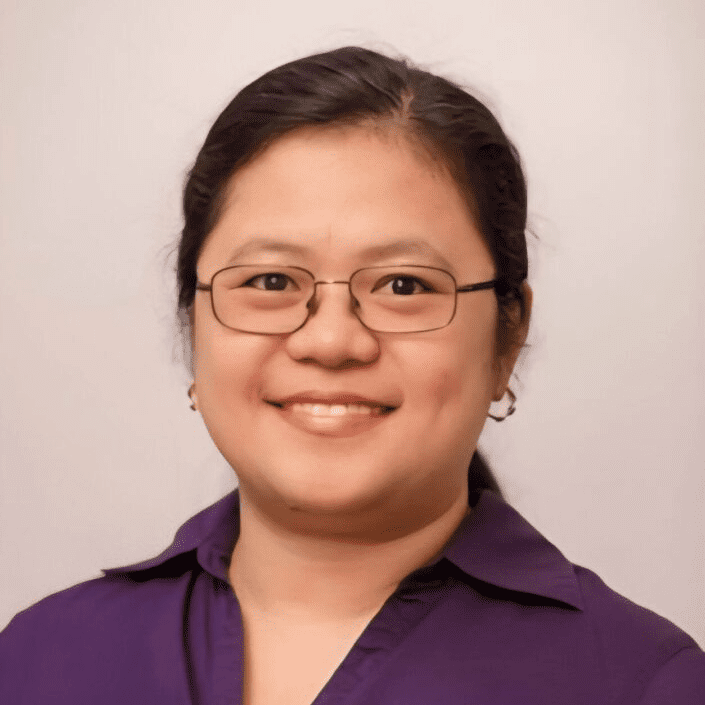 Smiling person wearing glasses and purple shirt.